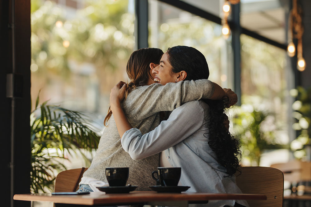 Two female friends meeting in a cafe social engagement for health